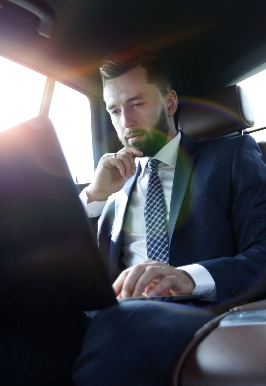 Man working on a laptop in the car